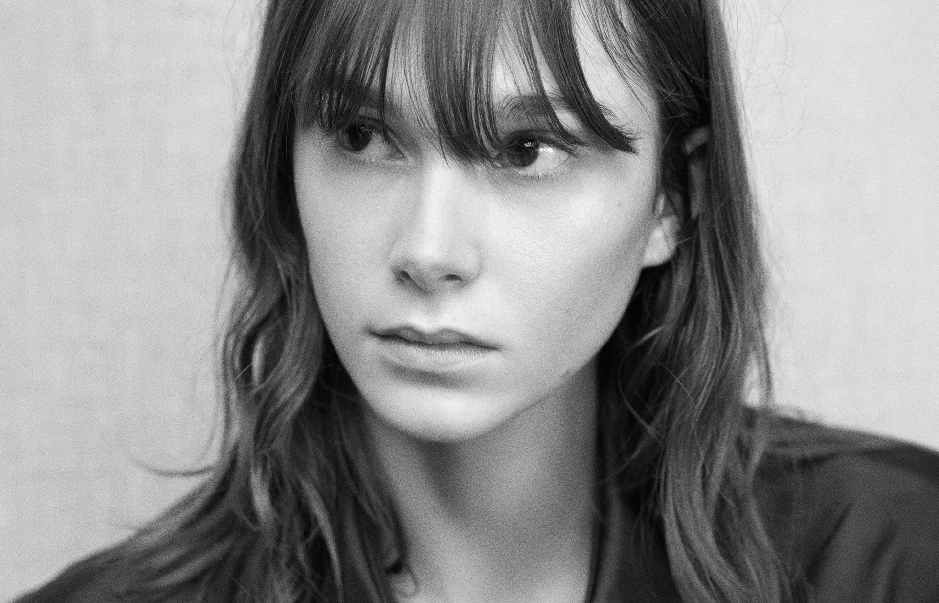 Black and white portrait of a person with shoulder-length hair, wearing a black shirt
