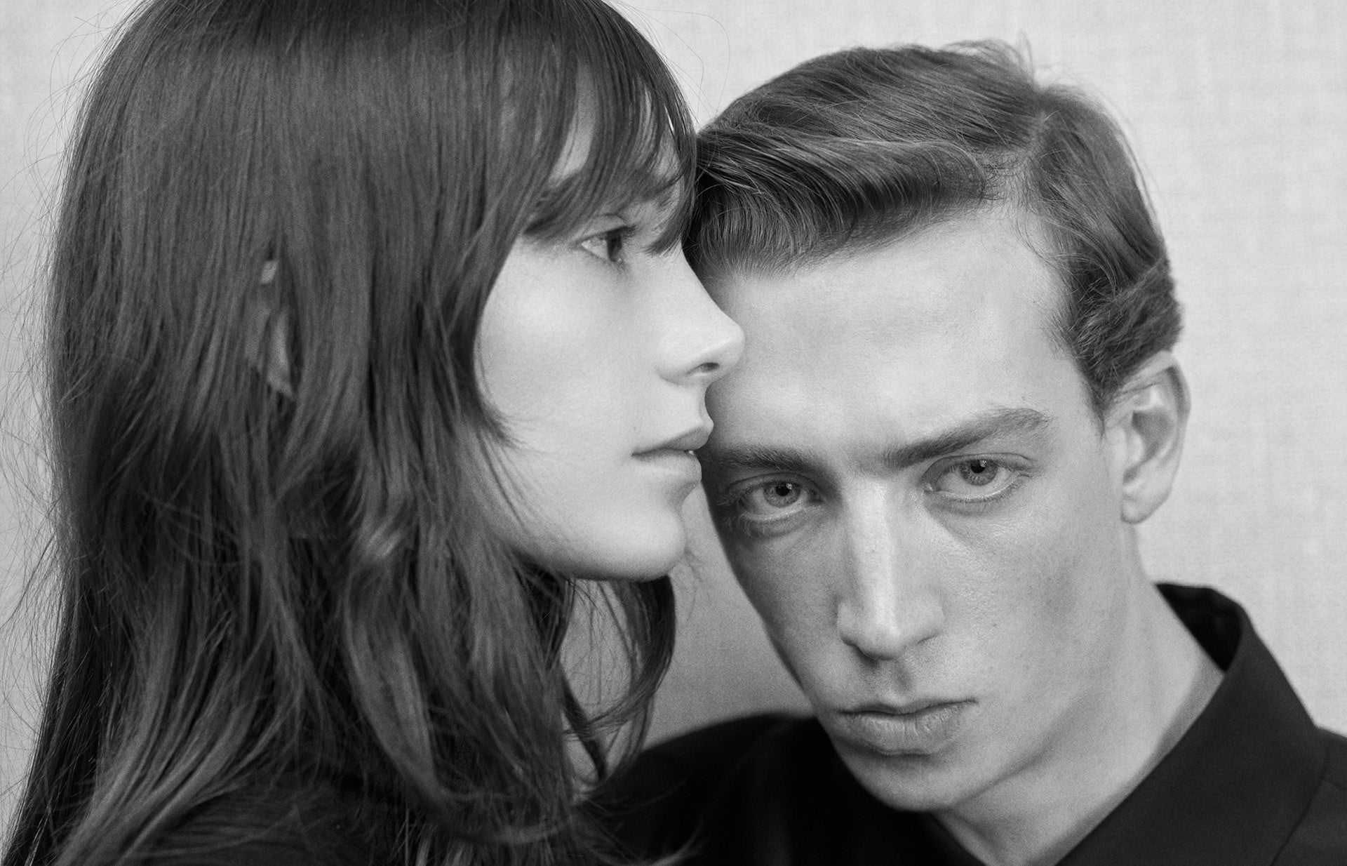 Black and white portrait of a man and a woman facing each other.